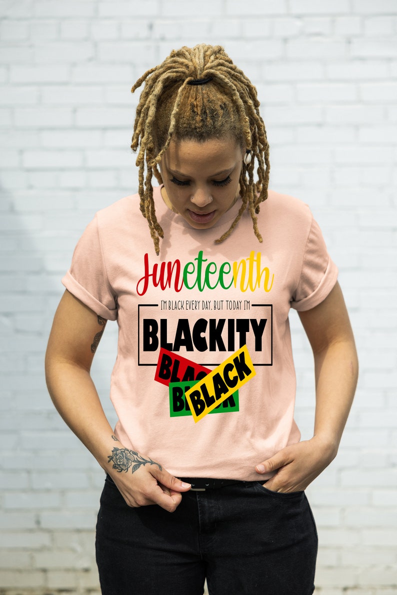 May include: A pink t-shirt with the text "Juneteenth" and "I'm Black every day, but today I'm Blackity Black Black" in black and red lettering.