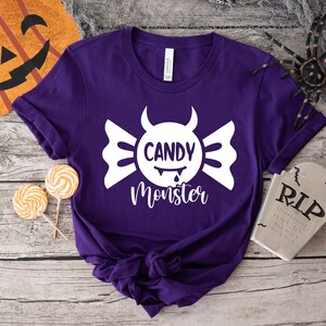 May include: Purple t-shirt with a white candy monster graphic and the text "Candy Monster".