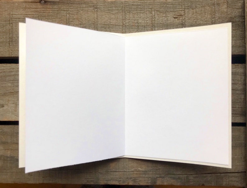 May include: Blank white card with a white envelope. The card is folded in half and the envelope is lying on top of the card.