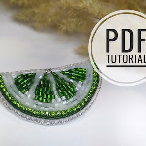 May include: A PDF tutorial for creating a beaded lime slice brooch. The brooch is made with green and white beads and has a shiny finish.