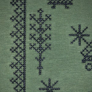 May include: Green fabric with black embroidered designs. The designs include a repeating pattern of geometric shapes, a tree, and stars.