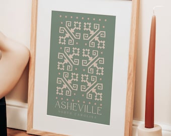 May include: A framed print with a green background and a geometric pattern in a light peach color. The print says "Asheville, North Carolina" in a light peach color.