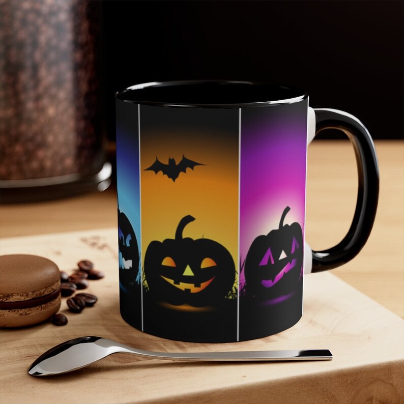 以下が含まれることがあります： ハロウィンをテーマにした黒いコーヒーカップ。カップには、カラフルな背景にコウモリのシルエットとジャック・オー・ランタンの南瓜4つが描かれています。