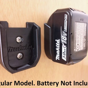 May include: Black plastic wall mount for a Makita 18V 3.0Ah Lithium-Ion battery. The mount has two screws and the text "Makita" is visible. The battery is not included.