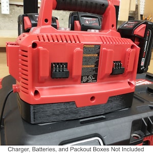 May include: Red power tool charger with two battery slots and a black power cord. The charger is sitting on a black tool box.  Charger, Batteries, and Packout Boxes Not Included.