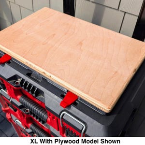 Puede incluir: Una tabla de madera contrachapada rectangular de color claro sobre un sistema de almacenamiento de herramientas modular negro y rojo. La unidad cuenta con pestillos de bloqueo rojos y asas negras. El texto XL With Plywood Model Shown aparece abajo.