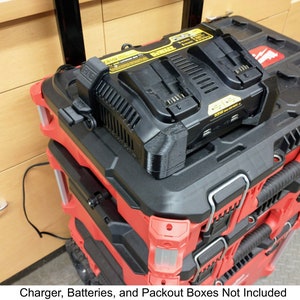 May include: A black and yellow DeWalt power tool charger mounted on top of a red and black tool box. The charger is plugged in and has a cord.