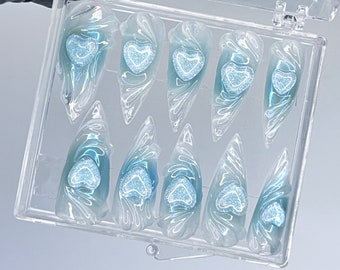 May include: A clear plastic box with 10 blue and white heart-shaped nail tips. The tips are arranged in two rows of five.