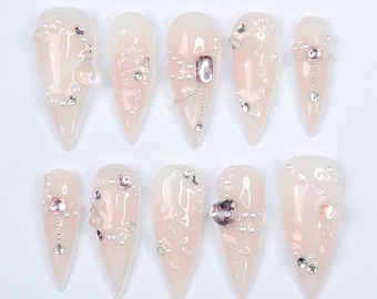 May include: Set of ten long, pointed, light pink false nails with intricate silver and pearl embellishments.