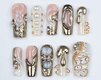 May include: Ten different nail designs featuring a variety of embellishments, including pearls, gold accents, and textured finishes. The nails are all long and almond-shaped.