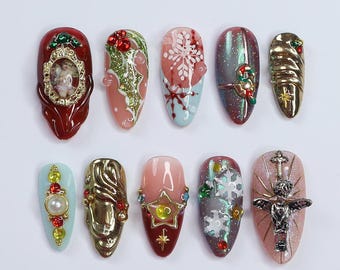 Könnte beinhalten: Zehn verschiedene Weihnachts-Nageldesigns. Die Designs beinhalten einen Schneeflock, Stechpalme, einen Stern, einen Zuckerstock, eine Glocke, einen Cherub, ein Kreuz und einen goldenen Wirbel. Die Nägel sind in Rot-, Weiß-, Blau- und Goldtönen lackiert.