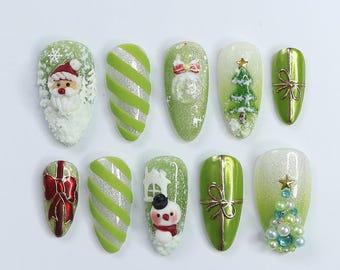 Könnte beinhalten: Zehn grüne und weiße Weihnachts-Nageldesigns. Die Designs beinhalten den Weihnachtsmann, einen Schneemann, einen Weihnachtsbaum, einen Zuckerstock, eine Geschenkbox und eine Schneeflocke.