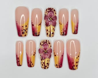 May include: Set of ten false nails with a leopard print design and a single flower accent nail. The nails are a light pink color with a burgundy ombre effect.