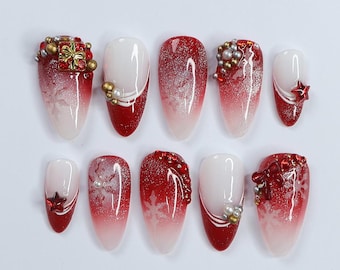 May include: Ten red and white ombre false nails with various Christmas-themed decorations, including snowflakes, bows, stars, and a gift box.