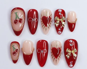 May include: Set of ten red and white false nails with various designs.  The designs include cherries, bows, hearts, and rhinestones.