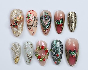 Könnte beinhalten: Zehn mandelförmige, dekorierte Fingernägel. Designs umfassen goldene, rote und grüne Weihnachtsmotive, Noten und ein Herz. Einige Nägel weisen 3D-Verzierungen auf, andere aufwendige Malereien.