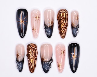 May include: Set of ten false nails with a variety of designs. Some nails are black with gold stars, some are pink with gold stars, and some are a metallic copper color.