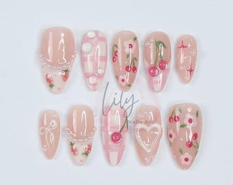 May include: Set of ten pink and white press-on nails with various designs including gingham, cherries, and flowers. The nails are decorated with small white pearls.