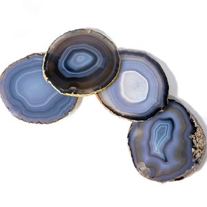May include: Four agate coasters with a gold trim. The coasters are in shades of gray and blue with a swirling pattern.