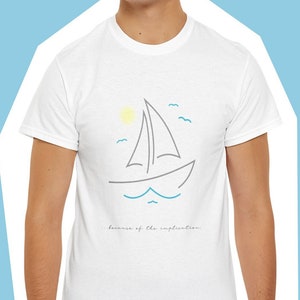 May include: White t-shirt with a simple line drawing of a sailboat on the water with a sun and birds. The text "because of the implausible" is printed below the sailboat.