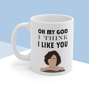 May include: White ceramic coffee mug with a black graphic of a woman with curly hair and the text "Oh my god I think I like you".