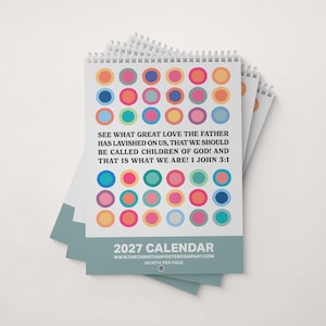 May include: A 2027 wall calendar with a white background featuring a grid of colourful circles in shades of pink, blue, orange, and yellow. The text reads: See what great love the Father has lavished on us, that we should be called children of God!