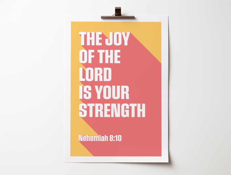 K&ouml;nnte beinhalten: Ein rechteckiger Druck mit dem Text "THE JOY OF THE LORD IS YOUR STRENGTH" in Wei&szlig;, vor einem korallenfarbenen und gelben Hintergrund. Der Text hat einen langen Schatteneffekt. Der Bibelvers "Nehemia 8:10" steht unten.