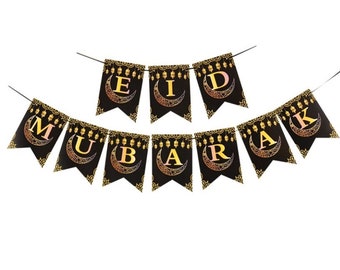 May include: Black and gold Eid Mubarak banner with crescent moons and lanterns. The banner is made of paper and has a string for hanging.