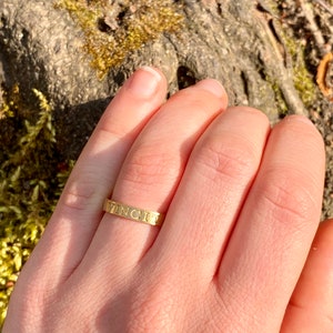 K&ouml;nnte beinhalten: Ein goldener Ring mit der Gravur "VINCIT" auf der Band.