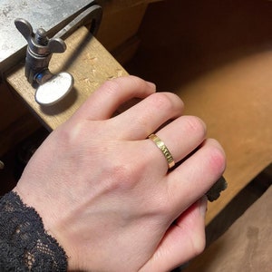 K&ouml;nnte beinhalten: Ein goldener Bandring mit der Gravur "AMOR".