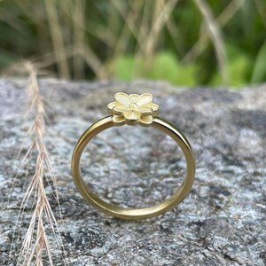 May include: A gold ring with a delicate flower design. The ring is simple and elegant, perfect for everyday wear.