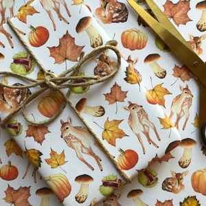 May include: White wrapping paper with a repeating pattern of brown and white deer, orange pumpkins, brown mushrooms, and brown and yellow leaves.