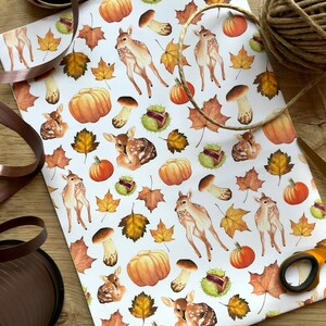 May include: White wrapping paper with a repeating pattern of brown and orange pumpkins, brown mushrooms, brown leaves, and brown deer.
