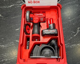 Könnte beinhalten: Roter Kunststoffkoffer mit einem roten und schwarzen Elektrowerkzeugsatz. Das Set enthält eine Kreissäge, einen Schleifer und einen Akku. Der Kofferdeckel trägt den Text "INSERT ONLY, NO TOOLS, NO BATTERY, NO BOX."