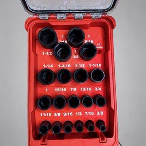 May include: A red plastic tool organizer insert with a clear hinged lid, containing various black metal socket wrenches. The insert features white printed labels for sizes ranging from 3/8 inch to 1-1/2 inches, plus a 1/2 inch adapter slot.