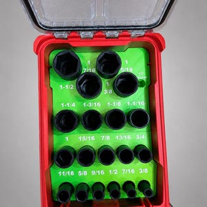 Op de afbeelding: Een felgroene kunststof dopsleutelorganizer in een rode behuizing met een doorzichtig deksel. Het inzetstuk heeft gelabelde sleuven voor diverse dopsleutelmaten van 3/8 tot 1-1/2 inch, voorzien van zwarte metalen dopsleutels in de openingen.