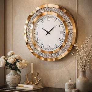 May include: A gold-framed wall clock with a white face and black Roman numerals. The clock's outer ring is encrusted with sparkling crystals. The clock is hanging on a beige wall, with decorative vases and candles on a table below.