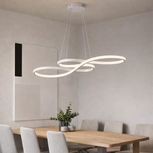 May include: White, modern, infinity-shaped LED pendant light fixture. The fixture is suspended from the ceiling by thin wires and illuminates a dining room with a wooden table and neutral-colored chairs. The light fixture has a unique, flowing design.