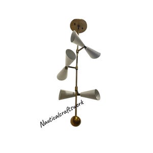 May include: A mid-century modern style ceiling light fixture. The light has a brass finish with five white cone-shaped shades. The fixture is suspended from a brass ceiling plate. The text "Nauticalcraftswork" is printed on the image.