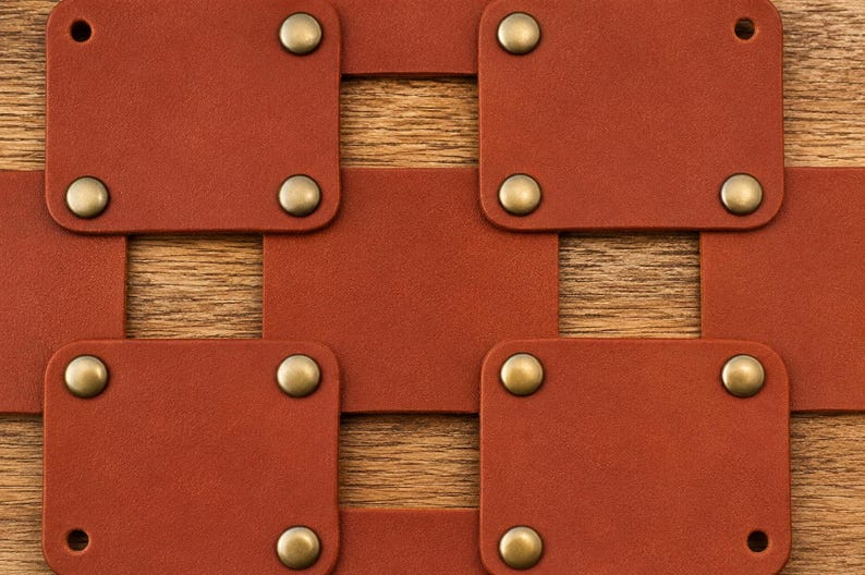 May include: A series of rectangular brown leather segments connected in a grid pattern by metallic brass-toned rivets. Each leather piece features rounded corners and a smooth matte finish, with the rivets securing the overlapping layers together.