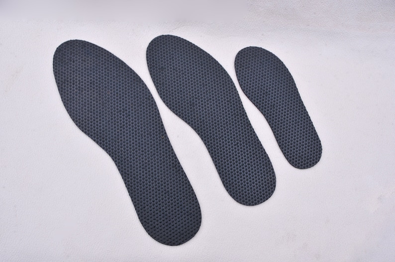 May include: Three black shoe insoles of different sizes. The insoles have a textured surface.