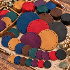 Puede incluir: Una colección de piezas de cuero circulares en varios tamaños y colores, incluyendo rojo, azul, verde, amarillo, morado, marrón y negro. Cada pieza presenta una serie de agujeros preperforados espaciados uniformemente en el borde exterior.