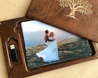 May include: A wooden box with a carved tree design on the lid. The box is open and contains a photo of a couple in a field and a USB drive.