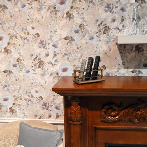 May include: A wooden fireplace mantel with a carved design and a shelf on top. The shelf has a metal remote control holder with four remotes inside. The wall behind the mantel has a floral wallpaper with a light blue and brown color scheme.