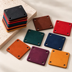 May include: A collection of square leather patches in various colors including black, brown, red, green, blue, orange, purple, and yellow. Each patch features four circular holes, one at each corner, designed for attachment to garments or accessories.