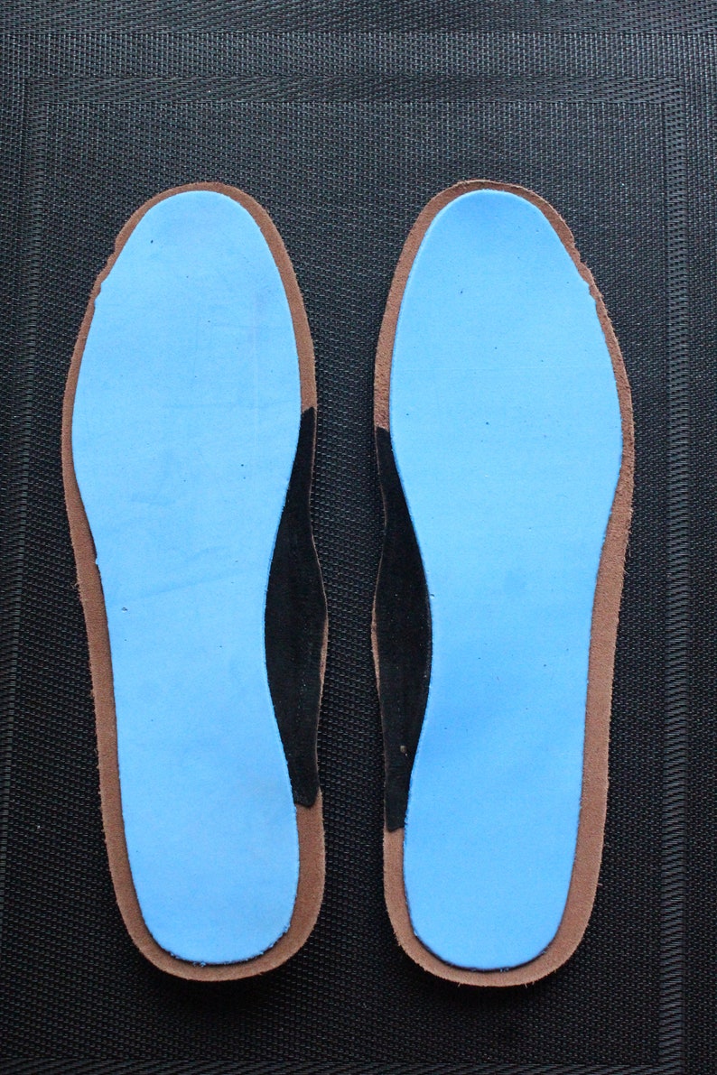 May include: A pair of blue shoe insoles with black arch support and brown edges.