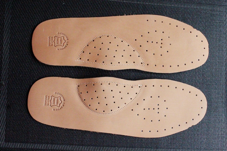 May include: Two brown leather insoles with a perforated design. The insoles have a circular logo that reads "Genuine Leather Hand Made Denmark".
