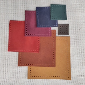 Puede incluir: Seis cuadrados de cuero de diferentes tamaños en varios tonos de marrón, rojo, verde y azul. Cada cuadrado tiene un borde cosido decorativo.
