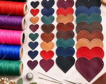 May include: A collection of leather heart-shaped cutouts in various sizes and colors, arranged in columns. Six spools of colored thread, two sewing needles, a metal thimble, and a leather awl are included for crafting projects.