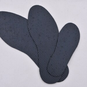 May include: Three black shoe insoles with a textured surface. The insoles are shaped like a foot and are designed to provide comfort and support.